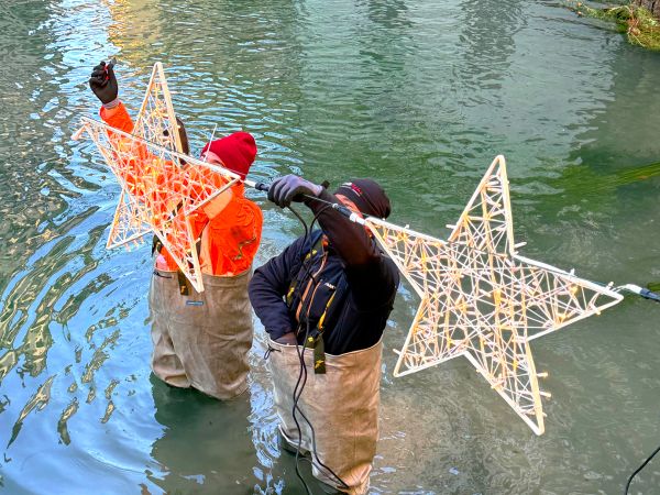 due allestitori in acqua mentre montano le luci di natale